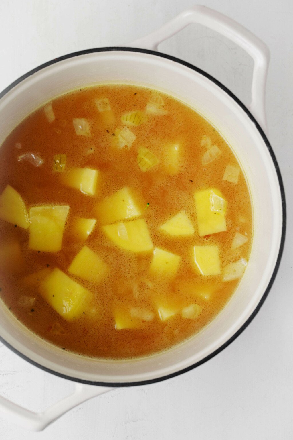 A large white pot holds hot broth and potatoes.