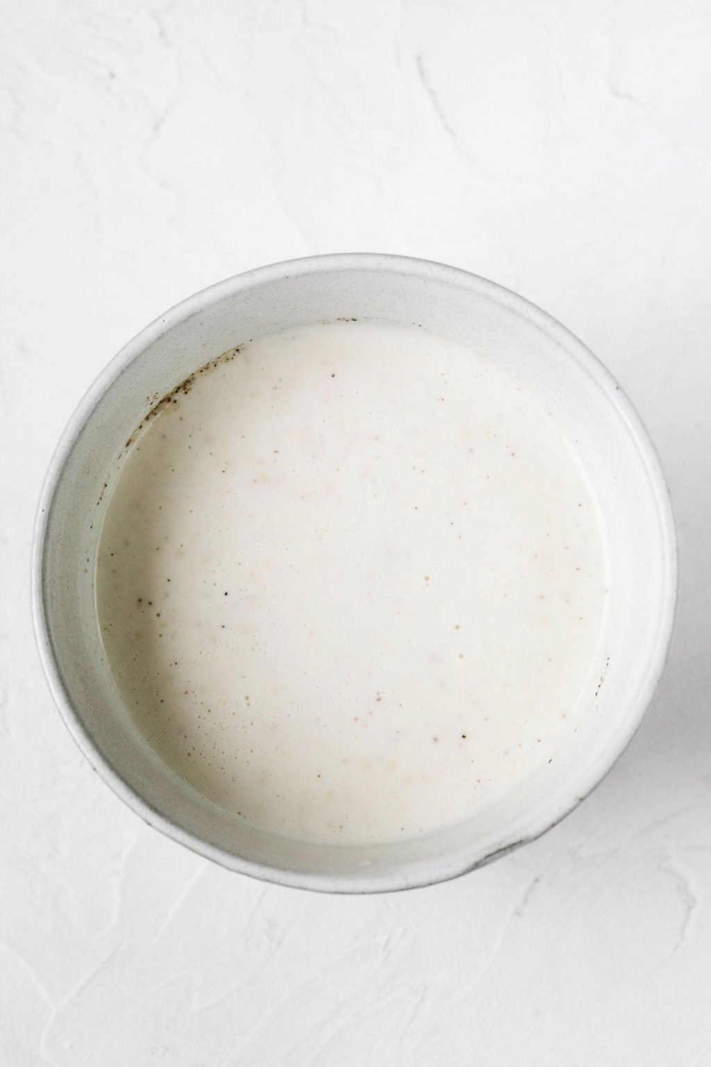 A white, ceramic pinch bowl is filled with a creamy, plant-based dressing.