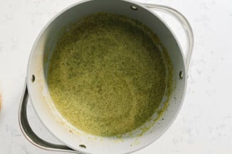 A large, gray pot holds a warm green soup.