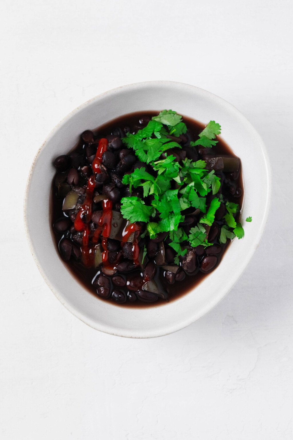 An overhead image of an asymmetrical white bowl, which has been filled with slow cooker black beans.