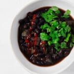 An overhead image of an asymmetrical white bowl, which has been filled with slow cooker black beans.