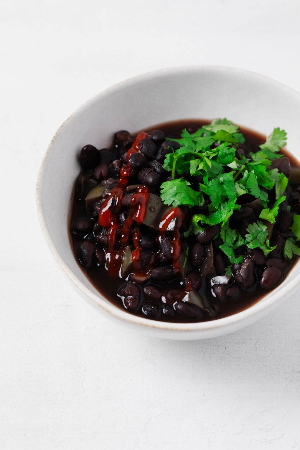 An overhead image of an asymmetrical white bowl, which has been filled with slow cooker black beans.