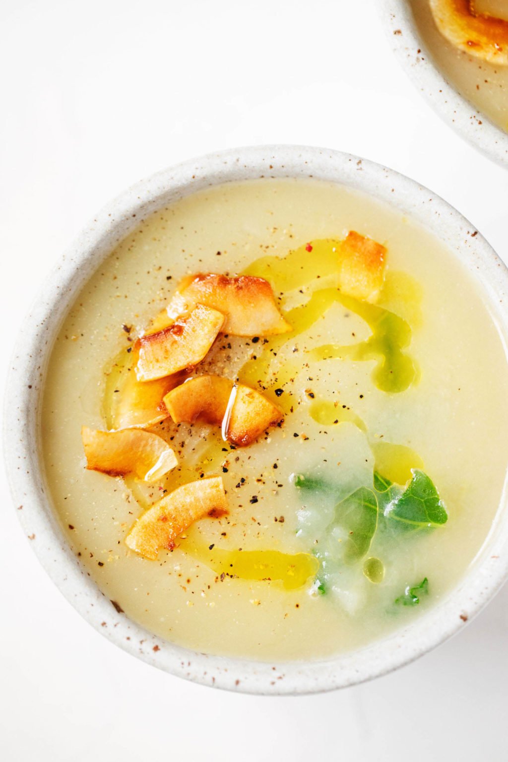 A close up, zoomed in image of a bowl of soup, topped with a plant-based coconut bacon and black pepper.