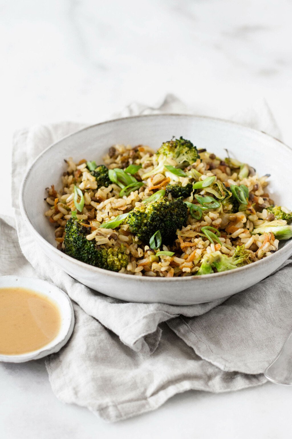 Sautéed broccoli, rice, and lentils have been served in a white ceramic bowl.