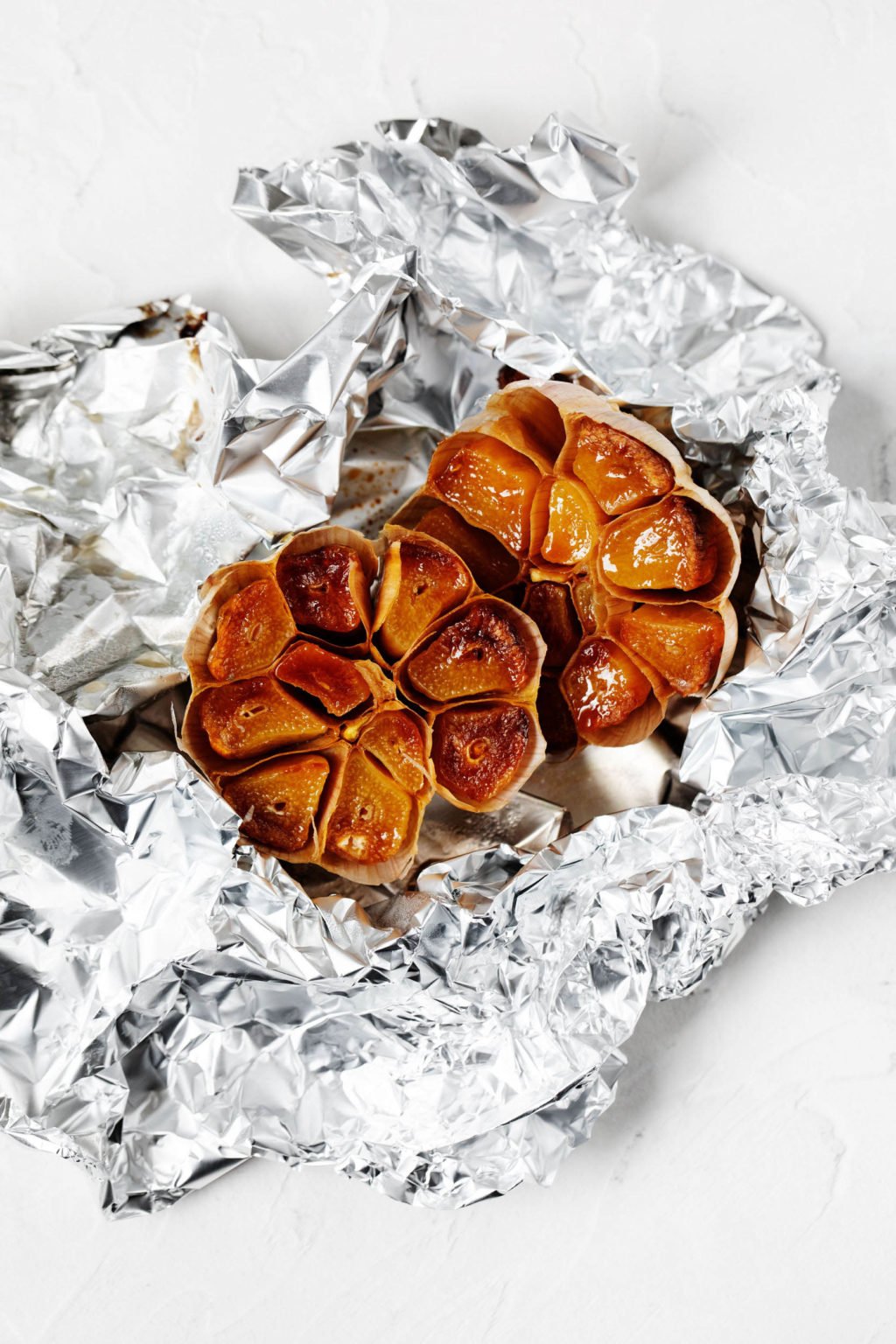 A head of roasted garlic has just been unwrapped from foil.