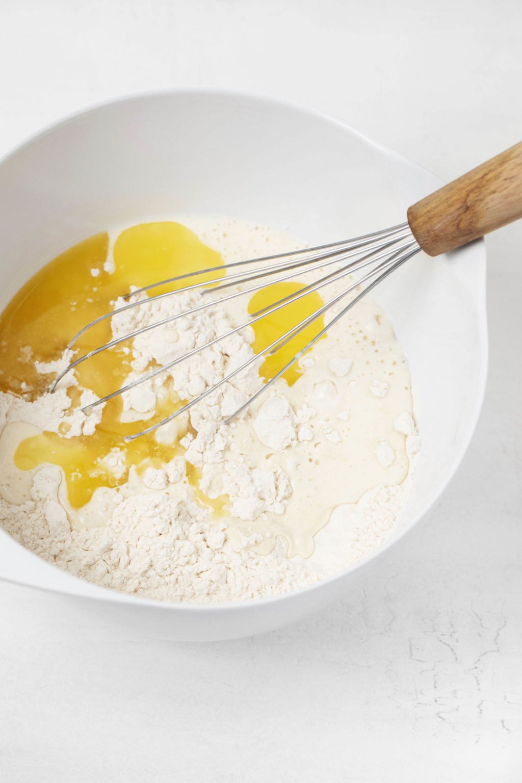 Un bol à mélanger contient de la farine, du beurre fondu et un fouet.