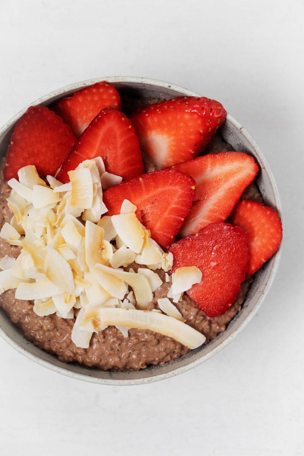 A close up, overhead image of a whole grain breakfast with coconut shreds and fresh fruit.