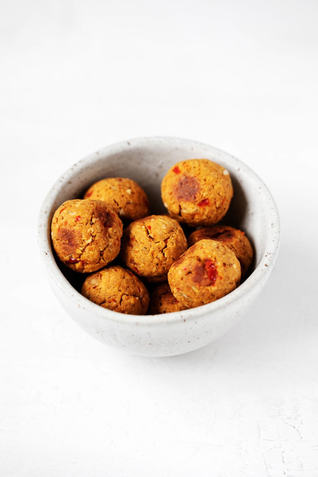 A small, ceramic bowl holds plant-based "meatballs" that have been prepared with chickpeas and oats.