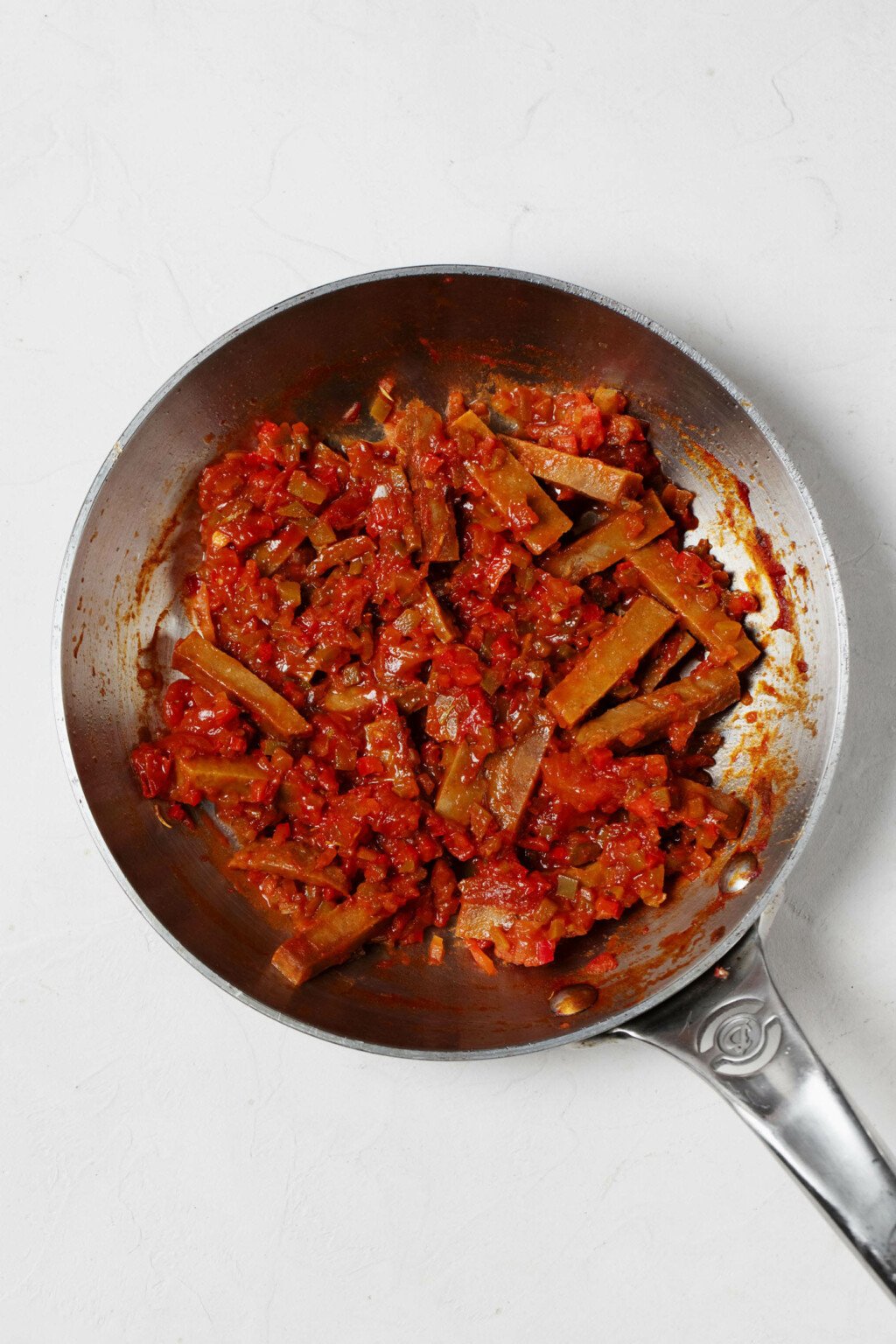An overhead image of a frying pan filled with a vegan protein and tomato sauce.