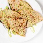 Artichoke white bean wraps have been cut into quarters and drizzled with a green sauce.
