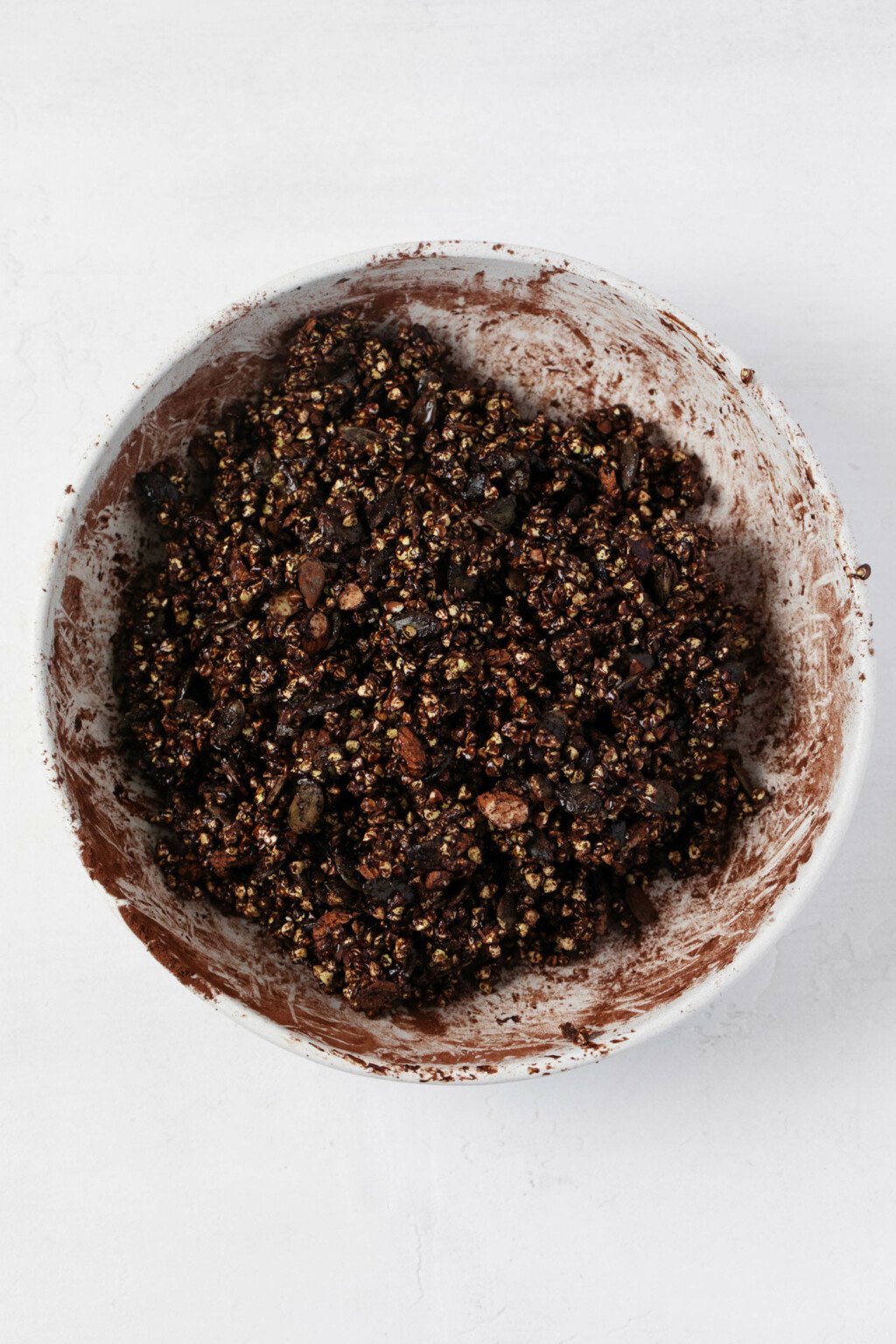 An overhead image of a large mixing bowl, which is being used to hold cocoa-flavored buckwheat granola.