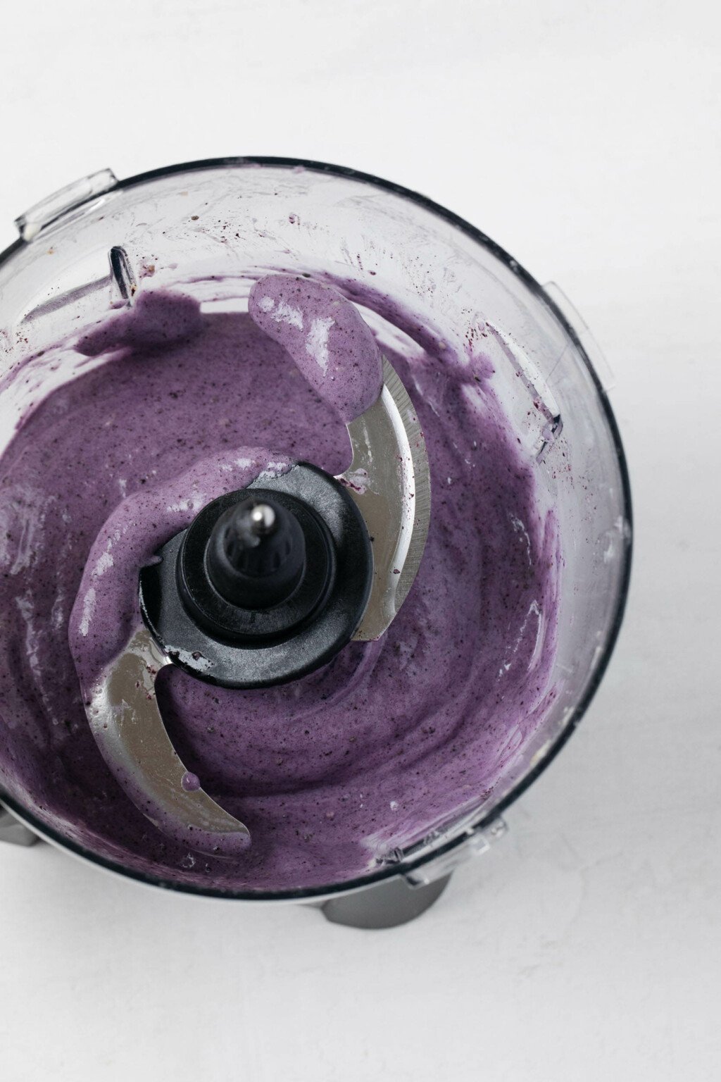 An overhead image of a food processor, which is filled with a creamy mixture of açaí and frozen bananas.
