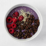 An overhead image of a colorful açaí bowl, which is topped with dark cocoa dusted buckwheat clusters.