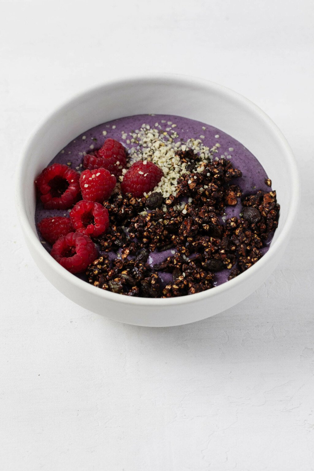 An overhead image of a colorful açaí bowl, which is topped with dark cocoa dusted buckwheat clusters.