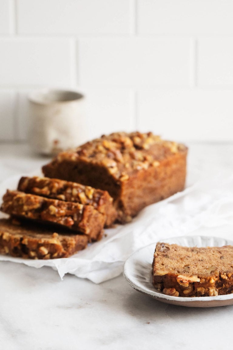 An angled photograph of classic vegan banana bread, sliced and ready to serve