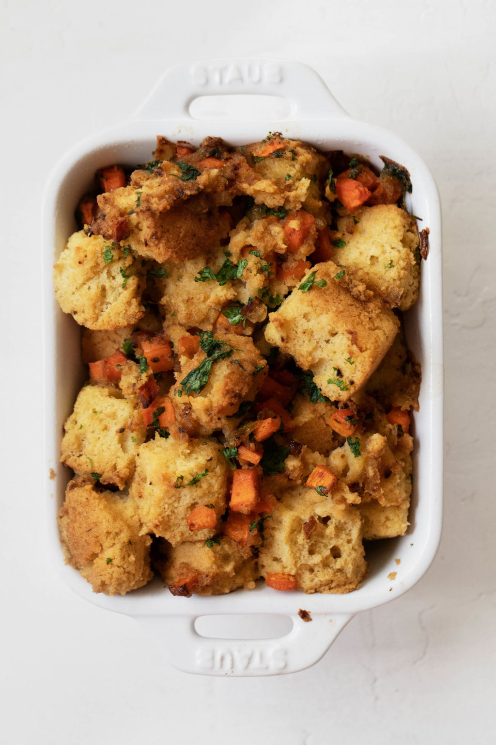 A small baking dish, filled with cornbread and vegetables.