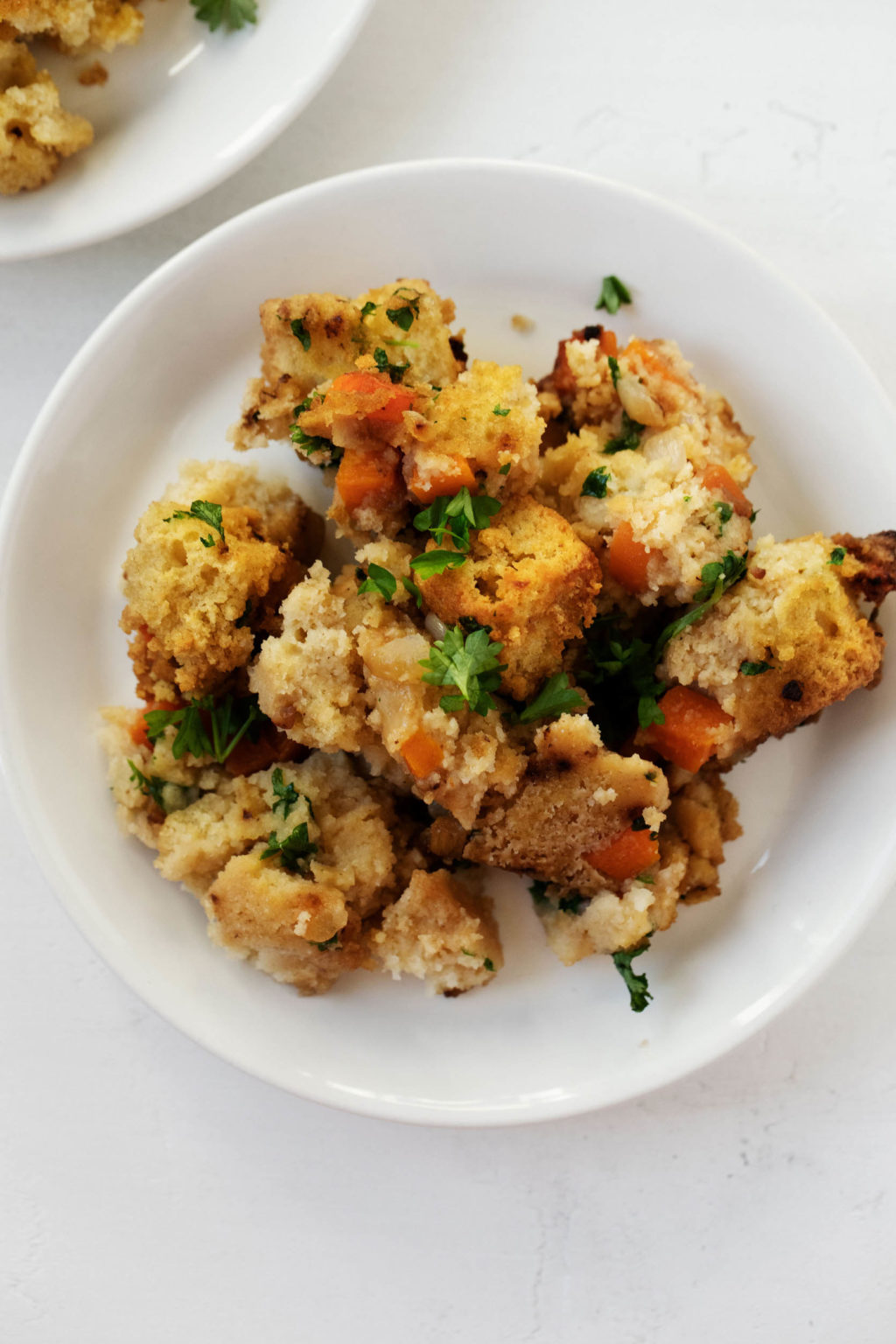 A serving plate, piled with a scoop of hearty cornbread stuffing and a sprinkle of fresh herbs.