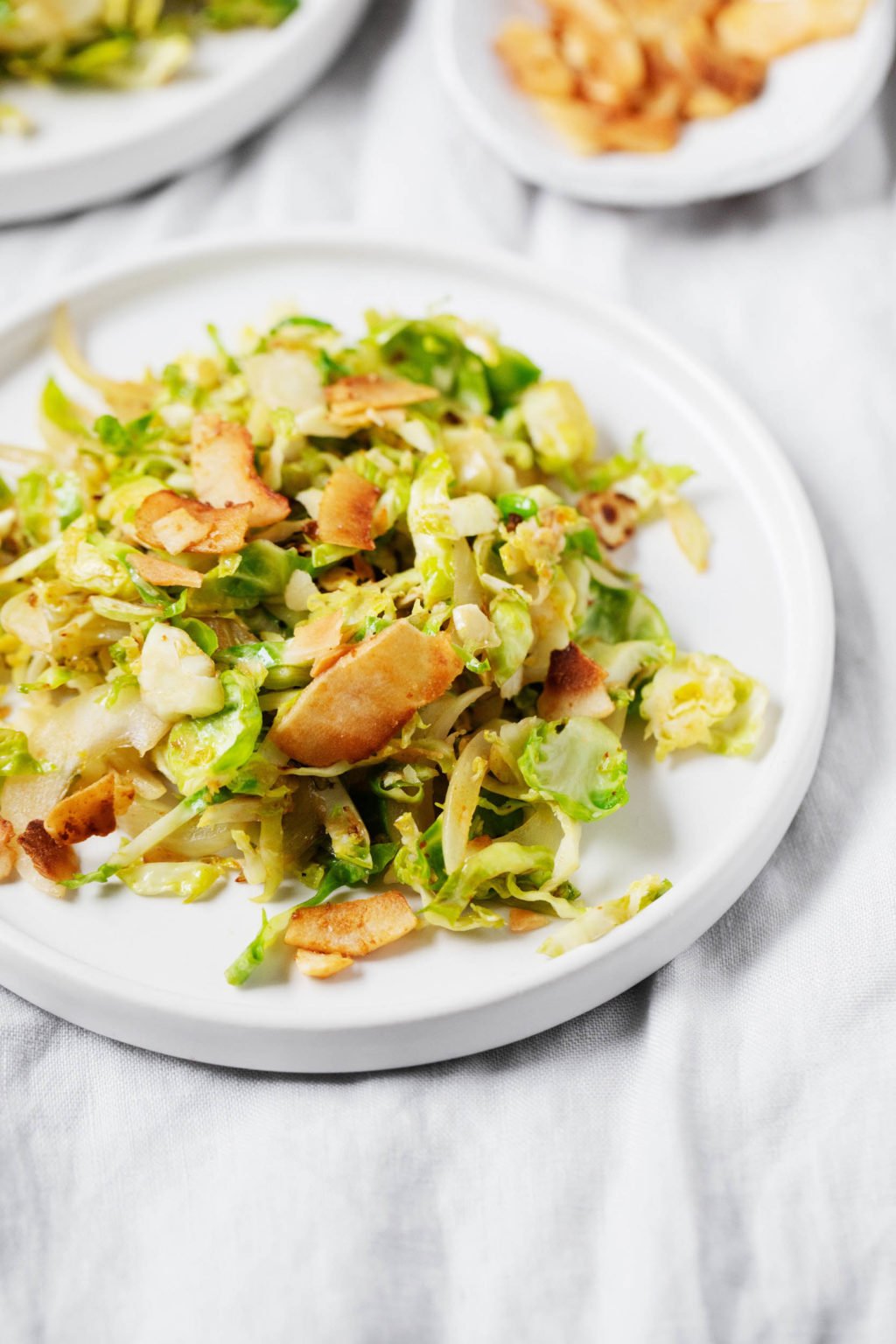 A plant-based side dish is laid out on a white serving plate and rests on a gray linen tablecloth.