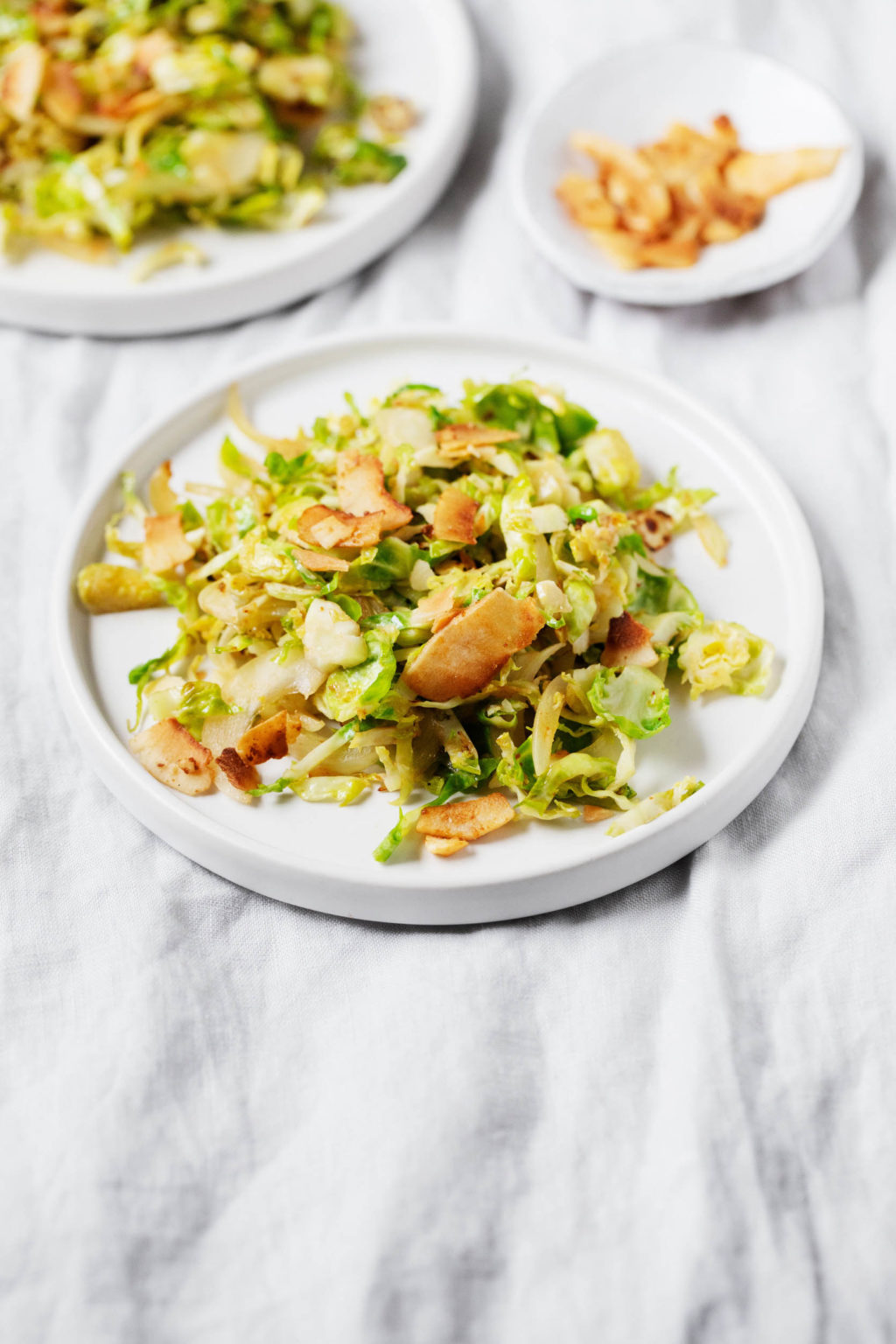 Several small, white side plates are topped with a plant-based hash, made with shaved Brussels sprouts.