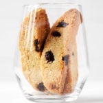 A clear glass holds several vegan cranberry almond biscotti.