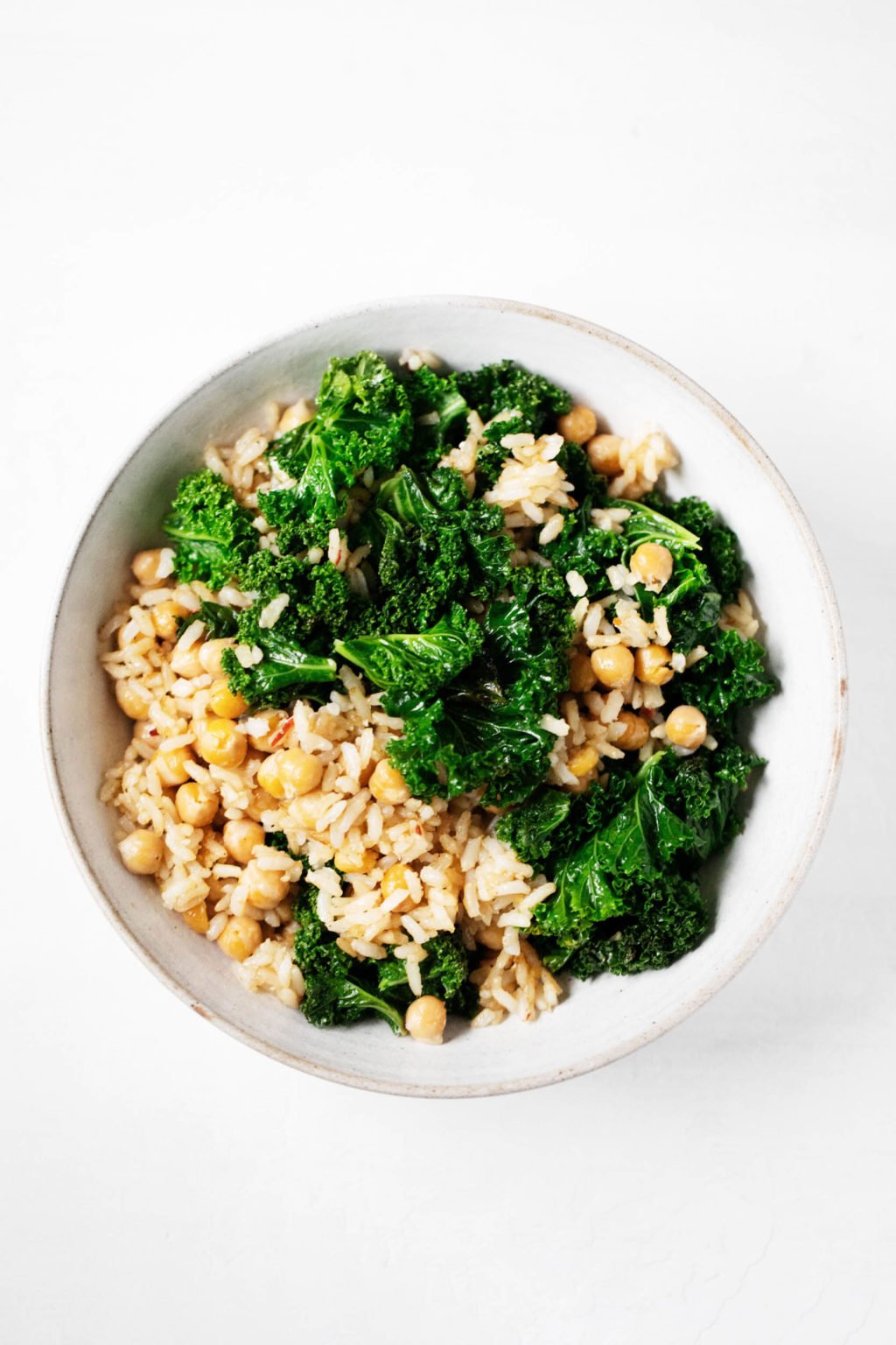 An overhead photograph of a bowl containing brown rice, greens, and chickpeas.