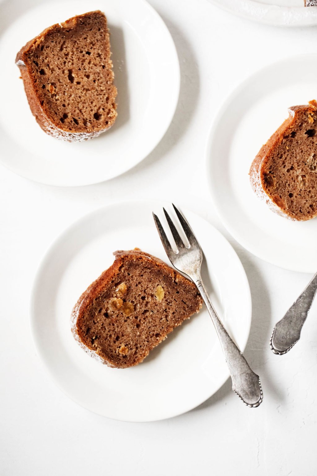 A few small white dessert plates have been topped with slices of a bundt cake.