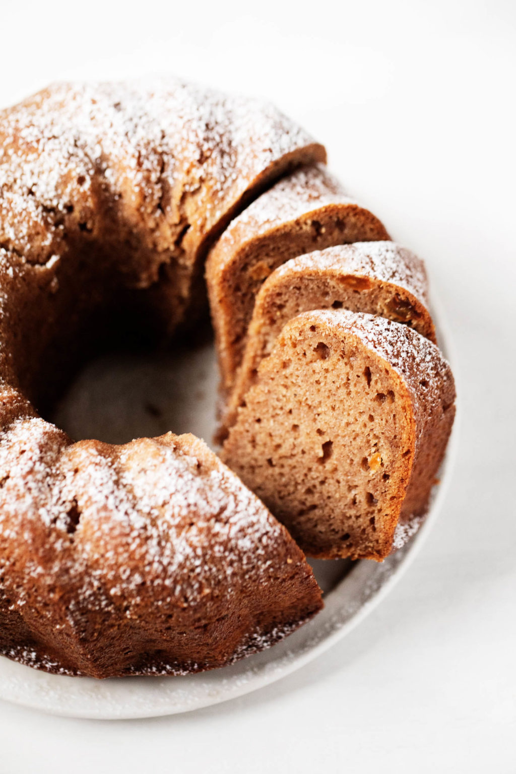 An applesauce spiced bundt cake has just been sliced into pieces for serving.