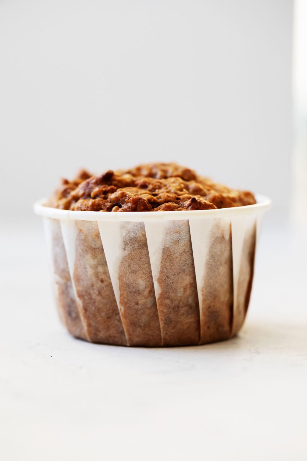 An angled photograph of a freshly baked vegan breakfast treat. It's positioned simply on a white surface.