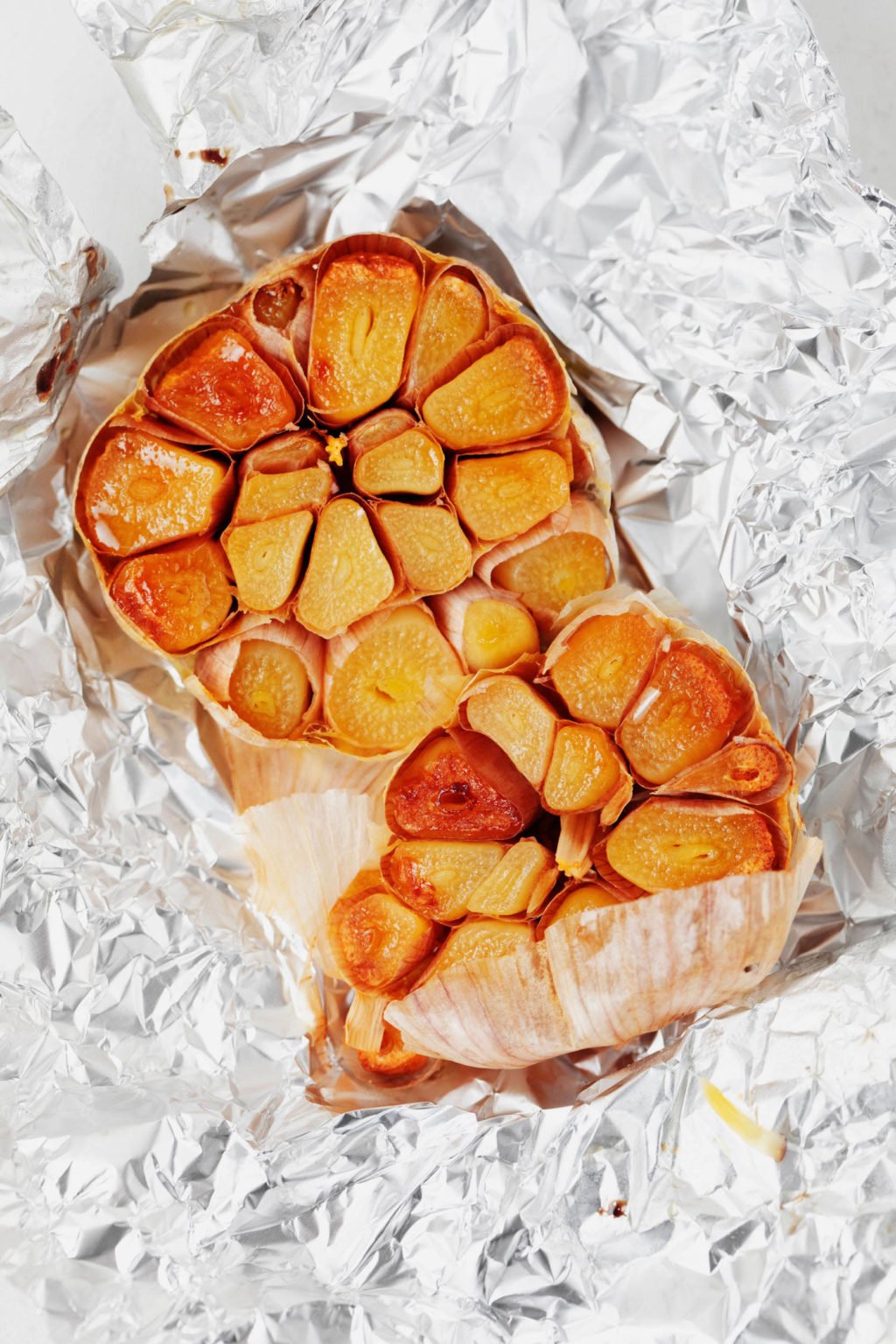 A bulb of roasted garlic lies in tin foil.