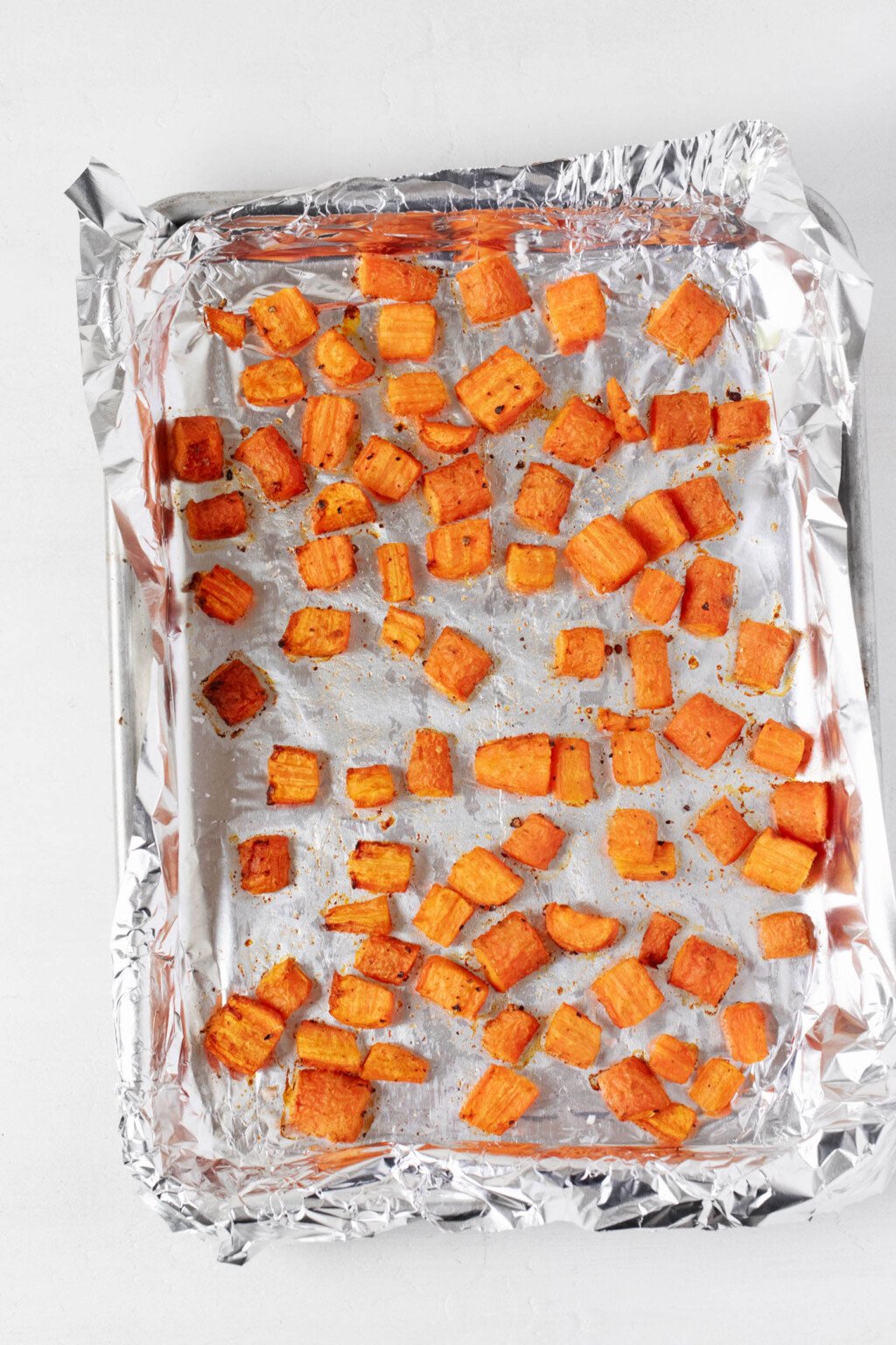 A foil-lined baking sheet is being used to roast a batch of carrots.