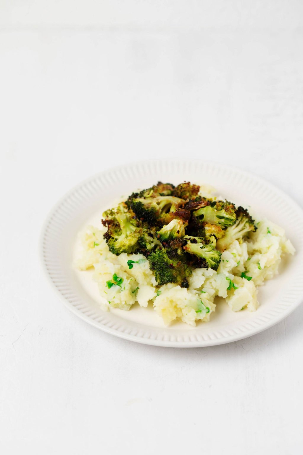 An angled photo of green and white vegetables, served on a rimmed white plate.