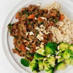 An overhead image of a plate of steamed broccoli, brown rice, and coconut curried green lentils.