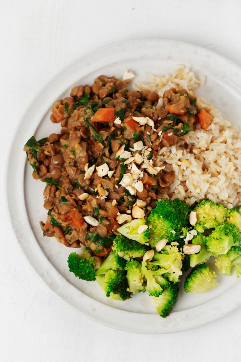An overhead image of a plate of steamed broccoli, brown rice, and coconut curried green lentils.