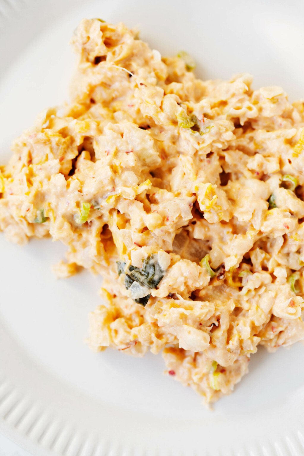 An overhead image of smashed chickpea salad, seasoned with plant-based mayonnaise and kimchi. It rests on a round white plate.