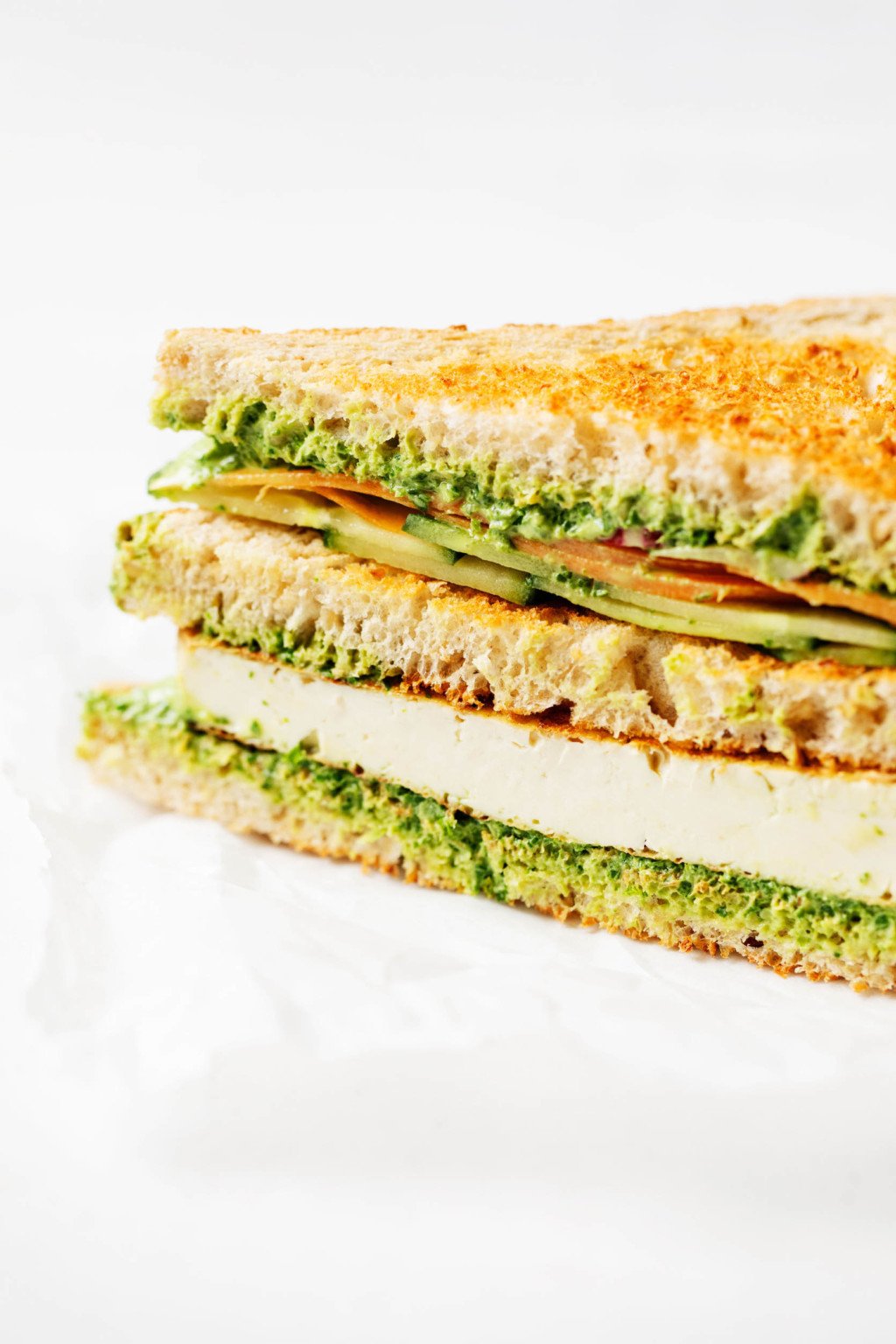 A crosswise slice of a three-layer sandwich on whole grain bread.