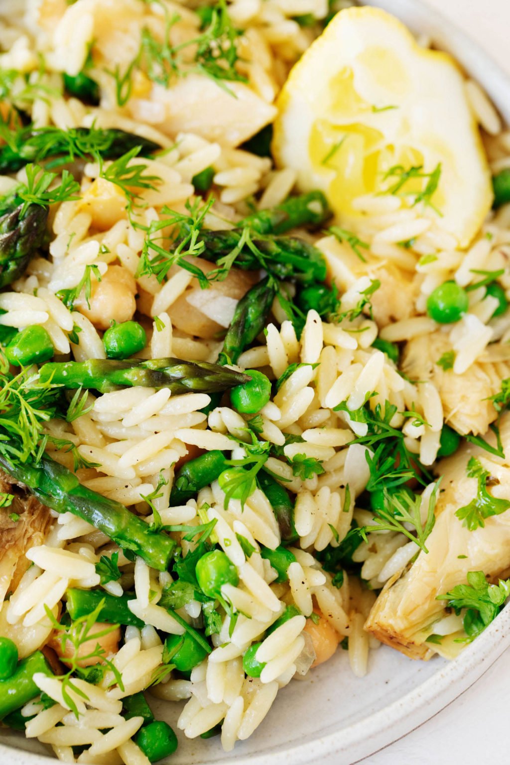 A close up photograph of orzo pasta salad, which has been dressed with olive oil and lemon and packed with fresh herbs.