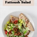 An image of a layered fattoush salad with crispy roasted chickpeas, which has been served in a shallow white bowl.