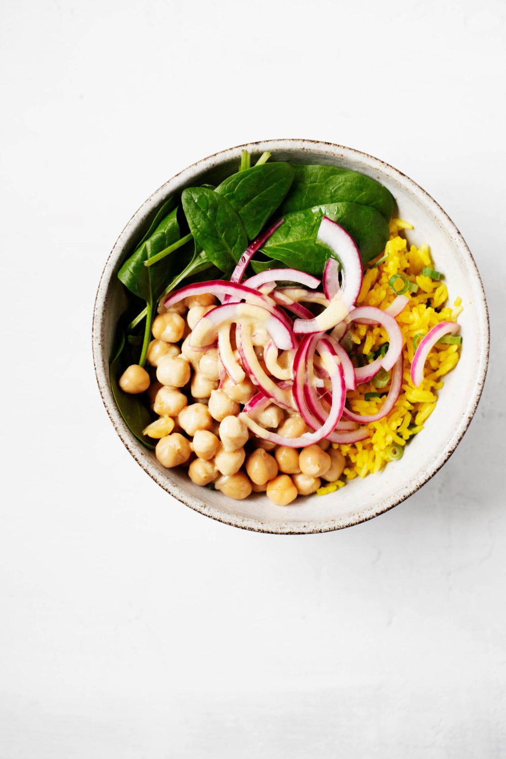 A small white bowl has been filled with rice, chickpeas, and vegetables.