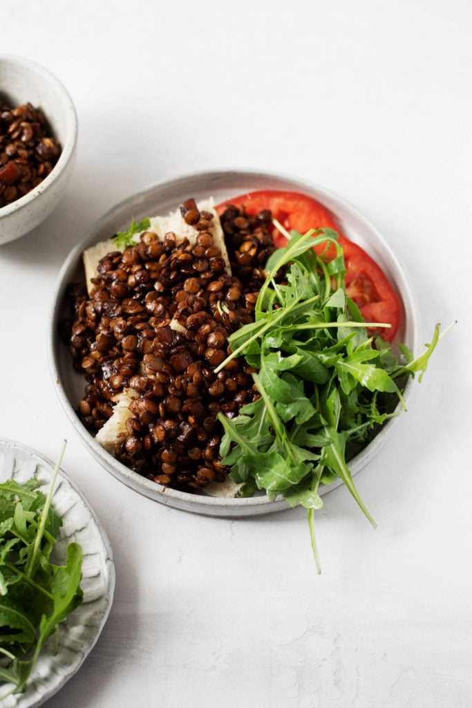 Braised lentils on toast, served with fresh, late summer tomato and arugula.