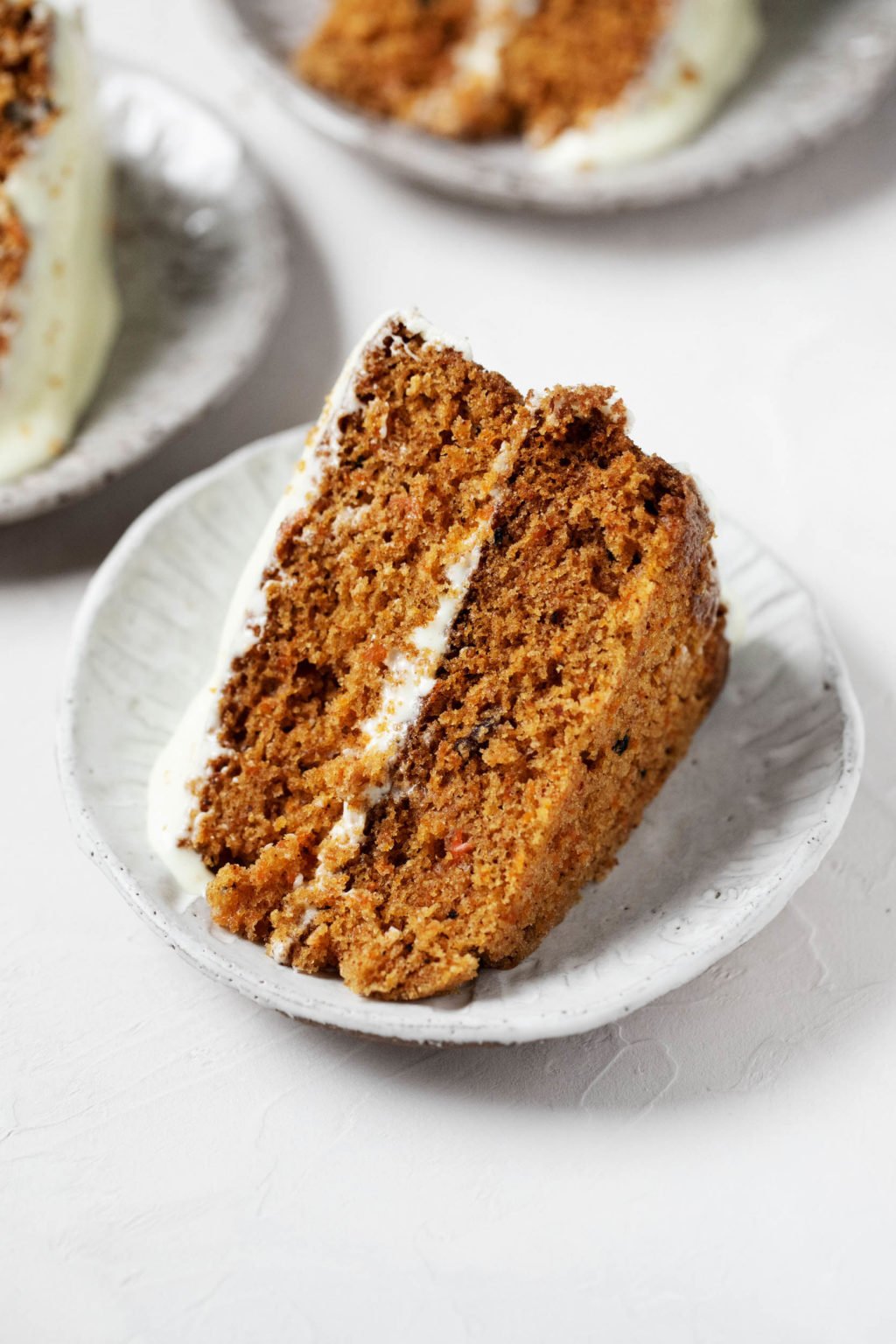 A few small plates, each with a slice of vegan pumpkin carrot cake.