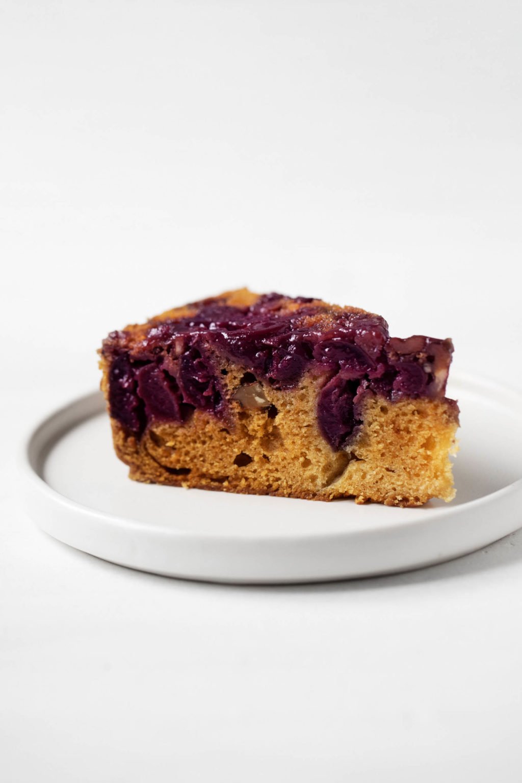An angled photograph of a neat slice of vegan cherry upside down cake.