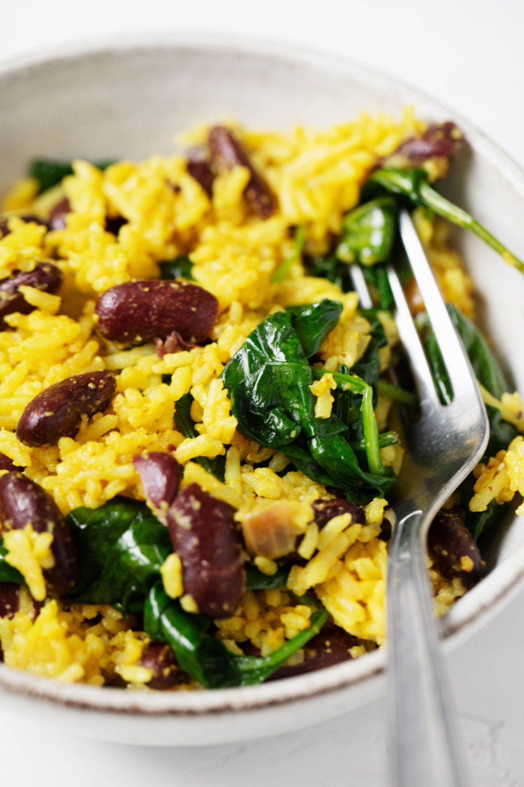 A close-up image of rice that's been cooked with turmeric, kidney beans, and spinach.