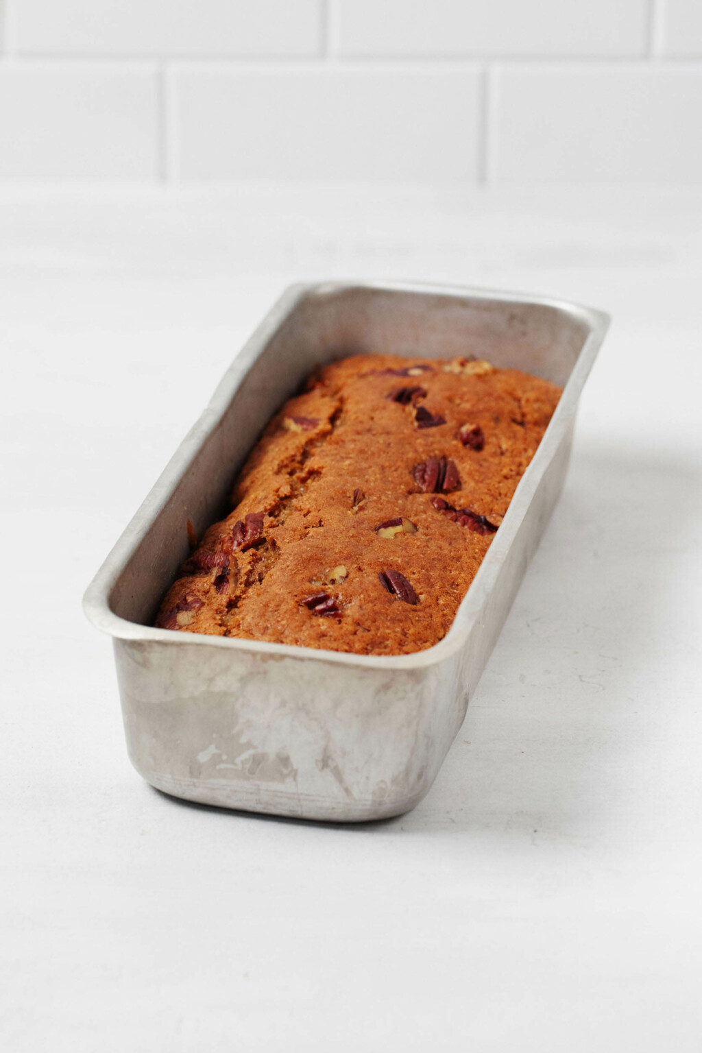 A metal loaf pan has been used to bake a spiced pecan citrus loaf.