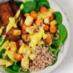 An overhead image of vegan harvest bowls, made with tempeh and root vegetables and drizzled with a mustard-based sauce.