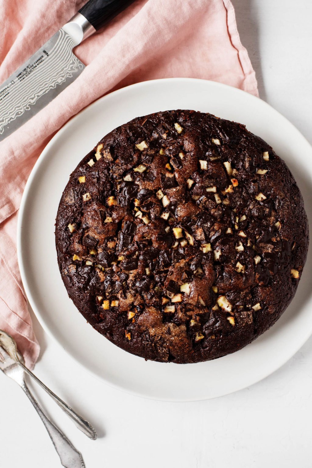 A vegan dark chocolate pear cakes rests beside a pink, linen napkin.