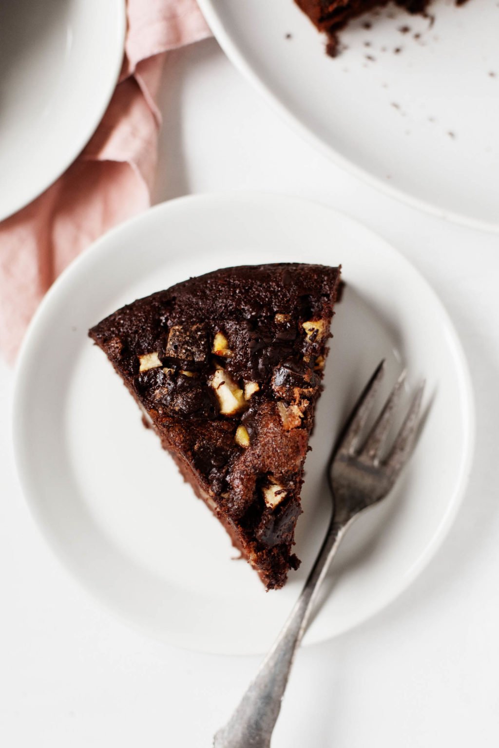 A neat slice of festive chocolate pear cake is perched on a dessert plate, with a small fork for serving. 