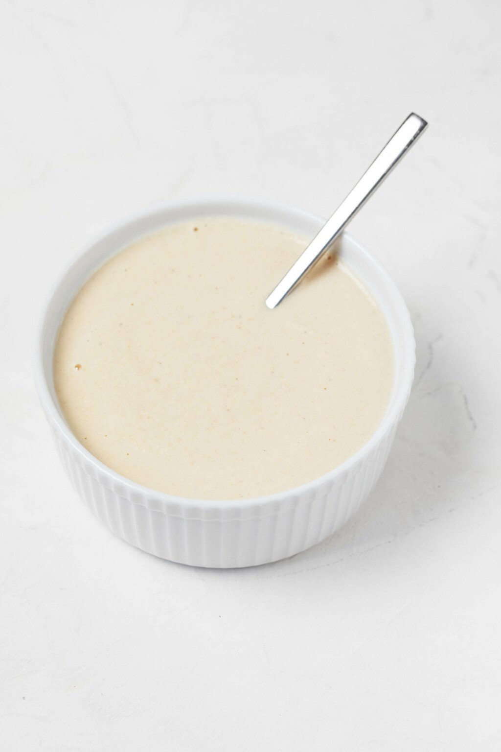 A round, white ramekin is filled with a vegan cashew whipped cream.