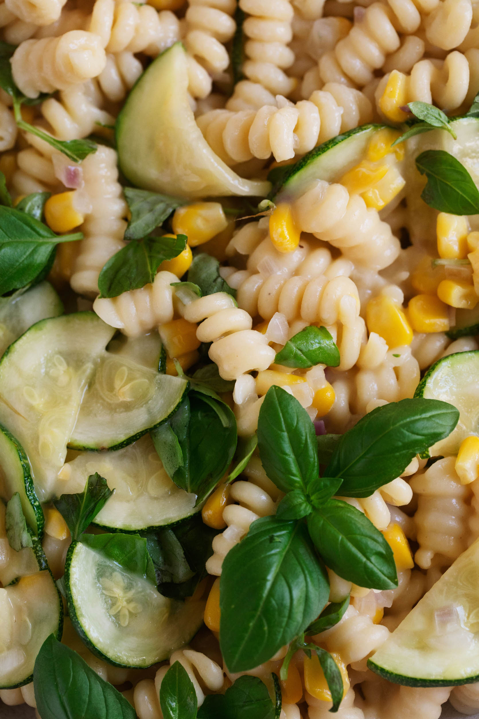 Zoomed in close up of a vegan pasta dish with zucchini, corn, and creamy sauce