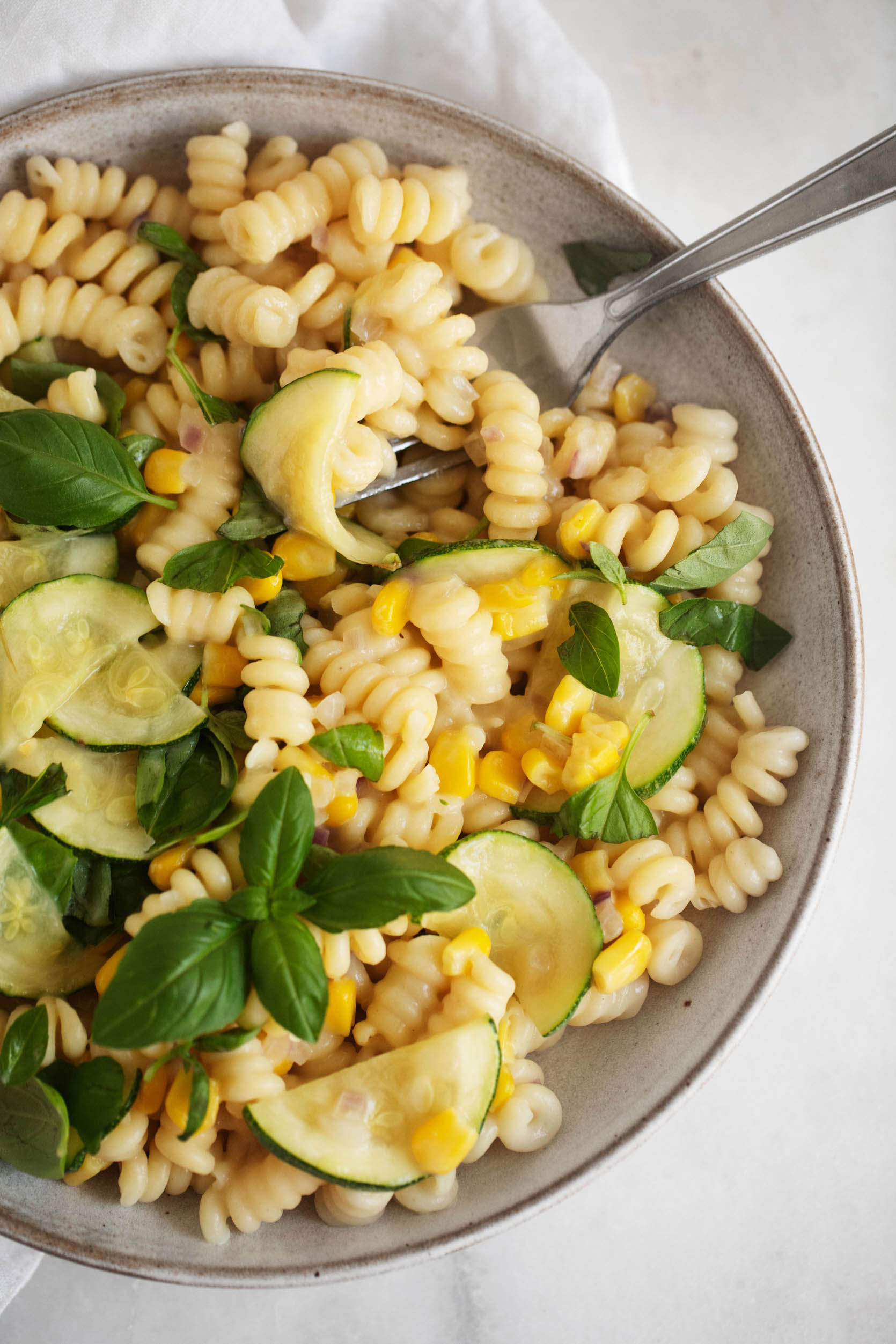 A vibrant dish of pasta with sweet summer corn, zucchini, and herbs