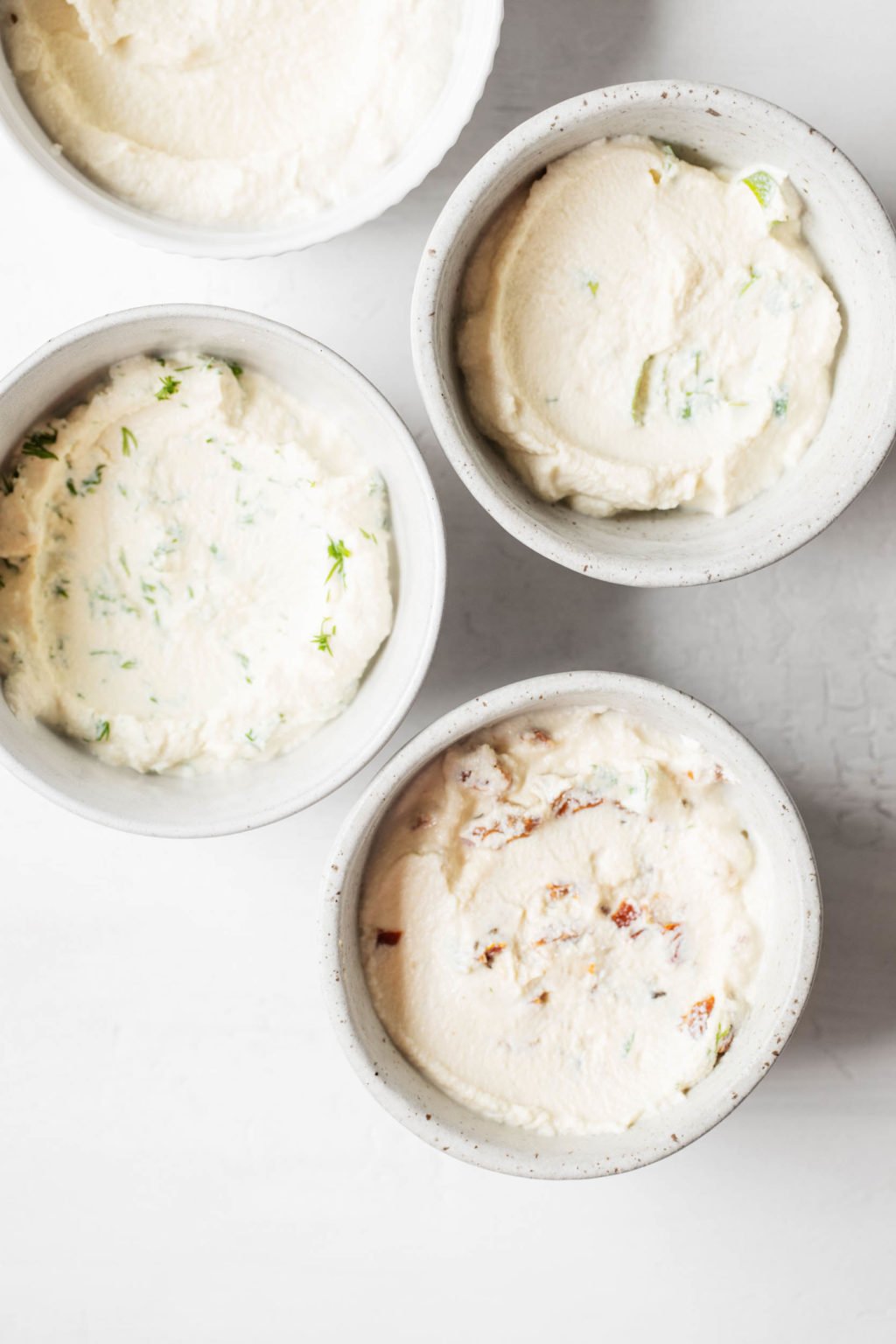 Four small, white ceramic pinch bowls are filled with a 5-ingredient tofu cream cheese.